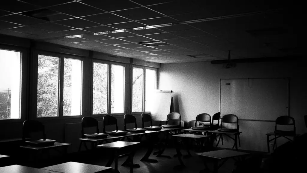 Une salle de classe vide avec des chaises et des bureaux alignés.