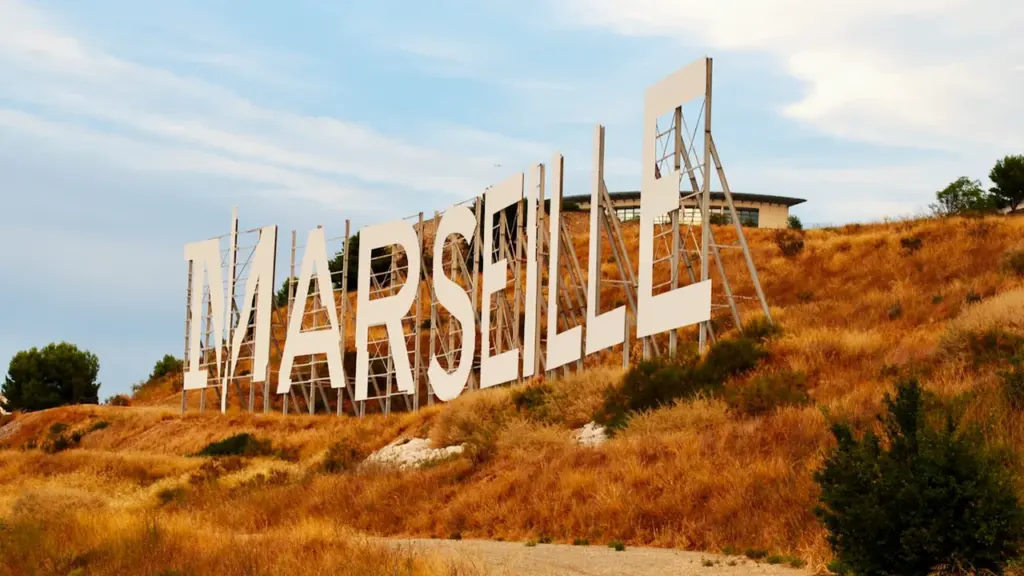 Grand panneau monumental indiquant le nom de la ville de Marseille dans le sud.