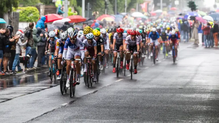Un peloton de cyclistes en plein effort sous la pluie lors d'une course sportive.
