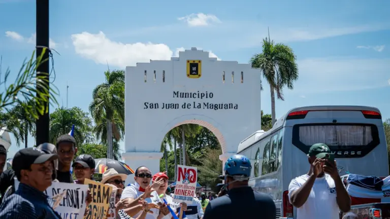 Des manifestants rassemblés devant une arche municipale avec un autocar à proximité.