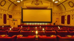 Salle de cinéma élégante avec des fauteuils rouges et un écran blanc vide.