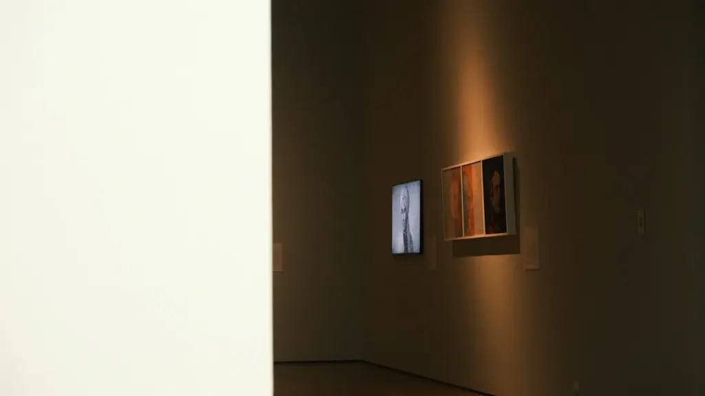 Galerie d'art moderne avec des œuvres encadrées éclairées par des spots lumineux.