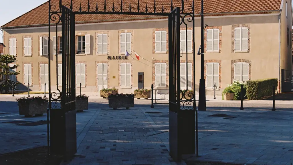 Bâtiment de la mairie avec un portail en fer forgé ouvert.