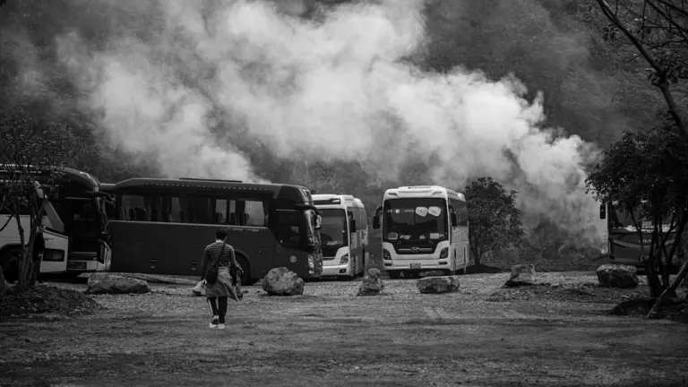 Plusieurs bus de transport garés dans une zone entourée par une épaisse fumée.