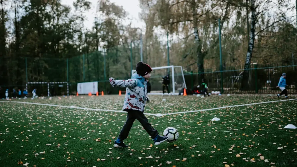 Un jeune enfant joue au football sur un terrain extérieur durant l'automne à Manosque.
