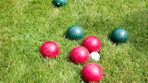 Plusieurs boules de pétanque rouges et vertes sur un terrain en herbe.