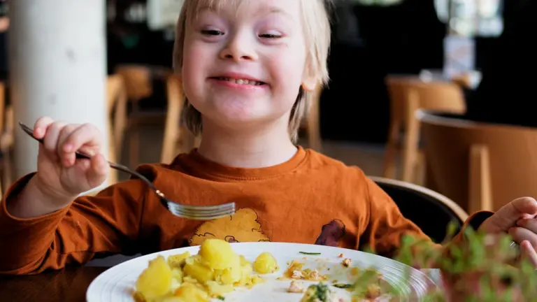Un jeune garçon souriant savoure un repas sain dans un restaurant.