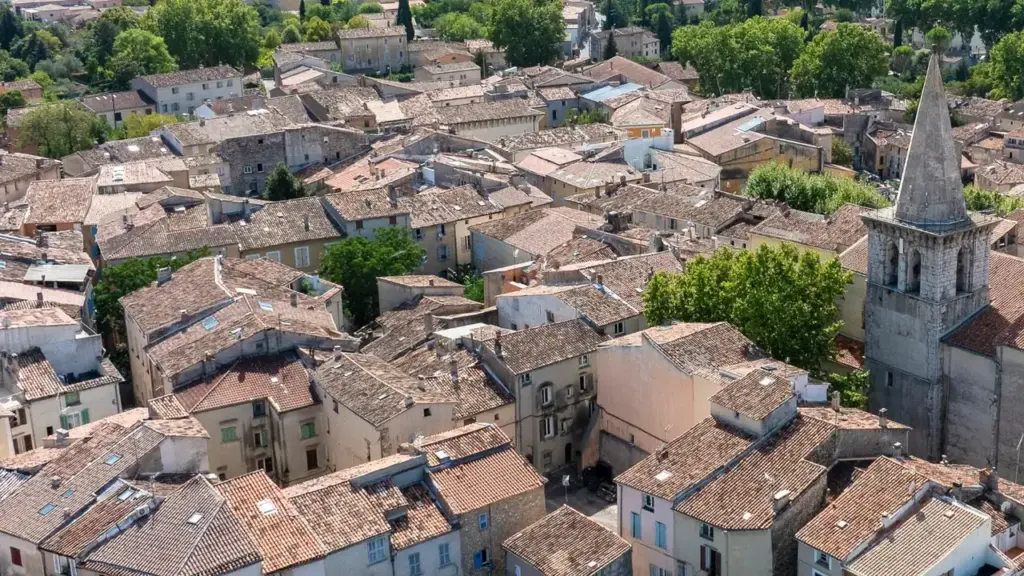 Vue aérienne d'un village provençal typique avec des toits en tuiles et un clocher.