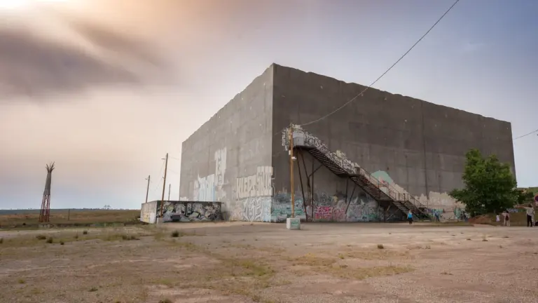 Un grand bâtiment en béton recouvert de graffitis avec un escalier extérieur sous un ciel.