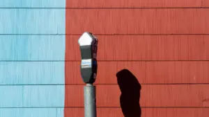 Un horodateur classique se dresse devant un mur bicolore rouge et bleu.