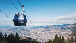 Une cabine de téléphérique moderne surplombant une vaste vallée et des forêts verdoyantes.